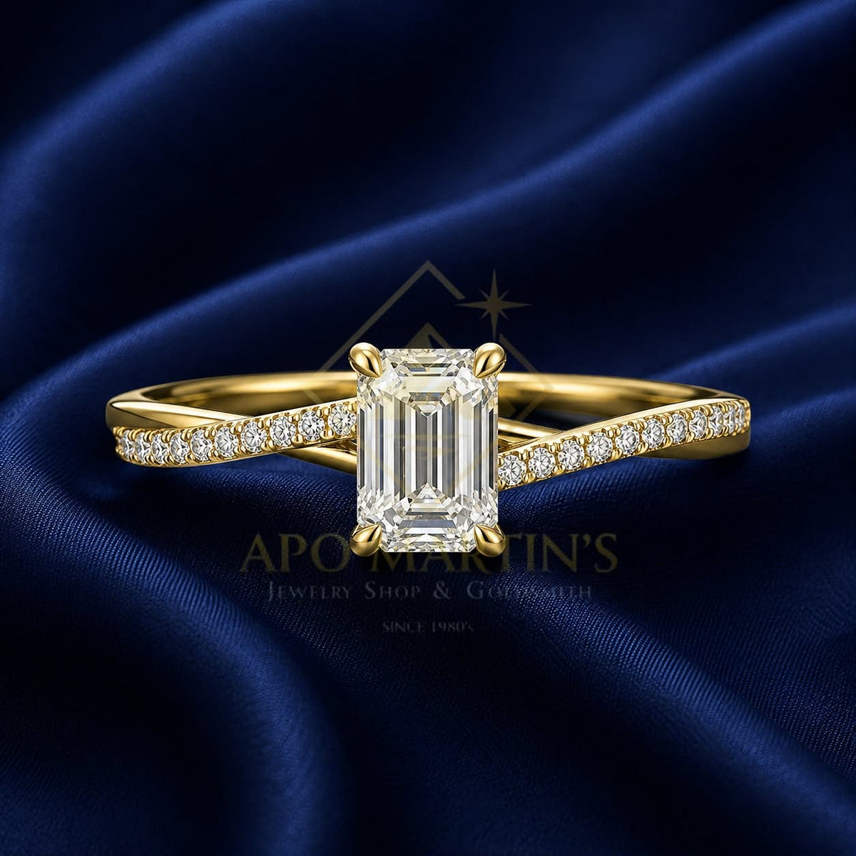 A yellow gold engagement ring with a large emerald-cut diamond center stone and pavé diamonds along the band, displayed on a draped dark blue satin fabric background. A watermark for 'APO MARTIN'S Jewelry Shop & Gemmology' is visible in the center.